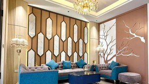 Una sala moderna con un sofá seccional, una mesa de centro redonda y un panel decorativo en la pared.