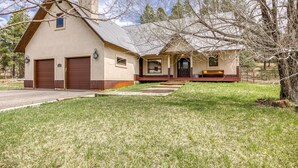 A two-story house with a front porch, a garage, and a small deck. - Mountain Views, Pet Friendly, New Hot Tub, Fenced Yard, Near Trails! (Pagosa Springs)