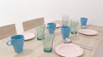 Ein Esstisch mit blauen und rosa Tellern, Gläsern und Besteck.