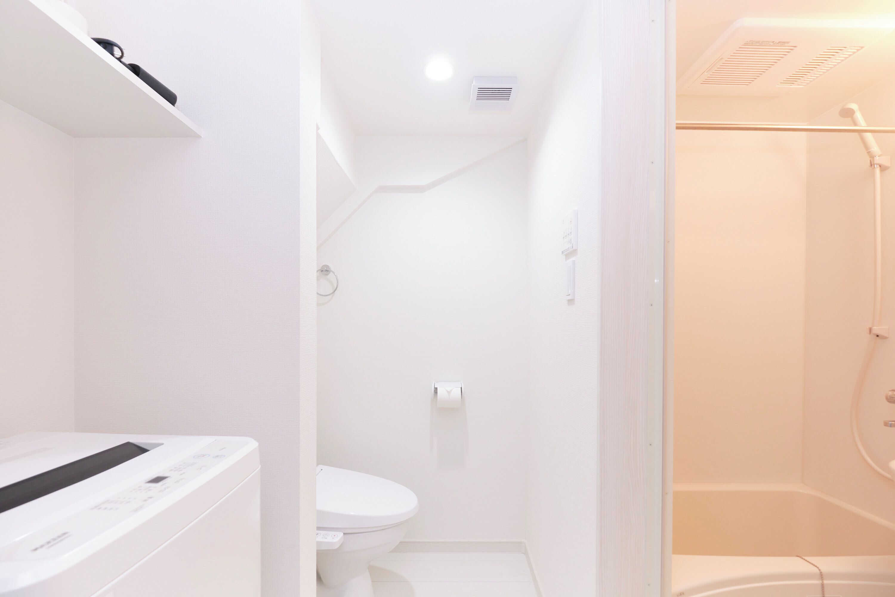 A modern bathroom with a toilet, a shower area, and a built-in washing machine.