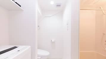 A modern bathroom with a toilet, a shower area, and a built-in washing machine.
