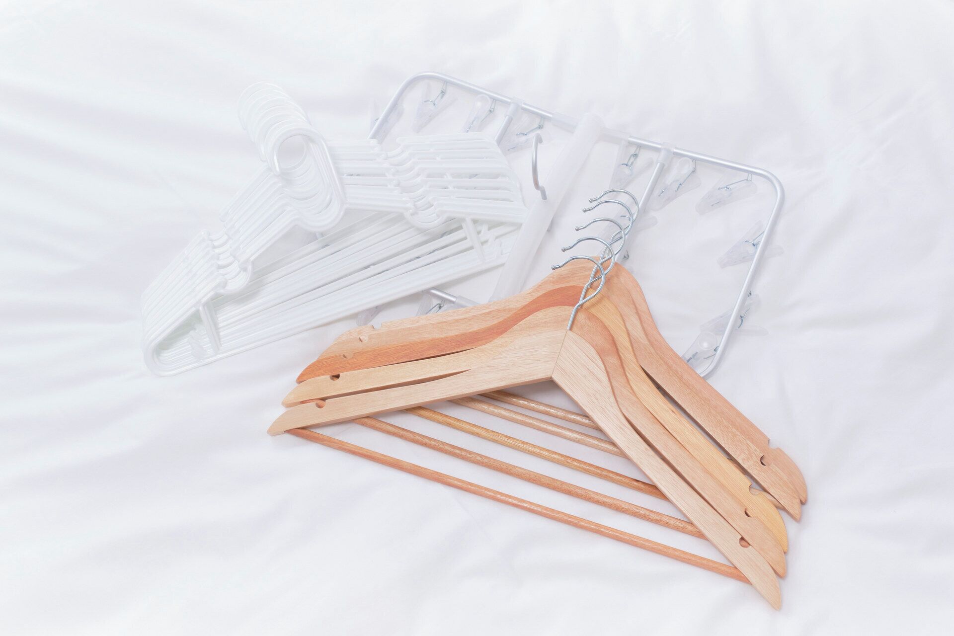 A set of wooden hangers and plastic hangers on a white surface.