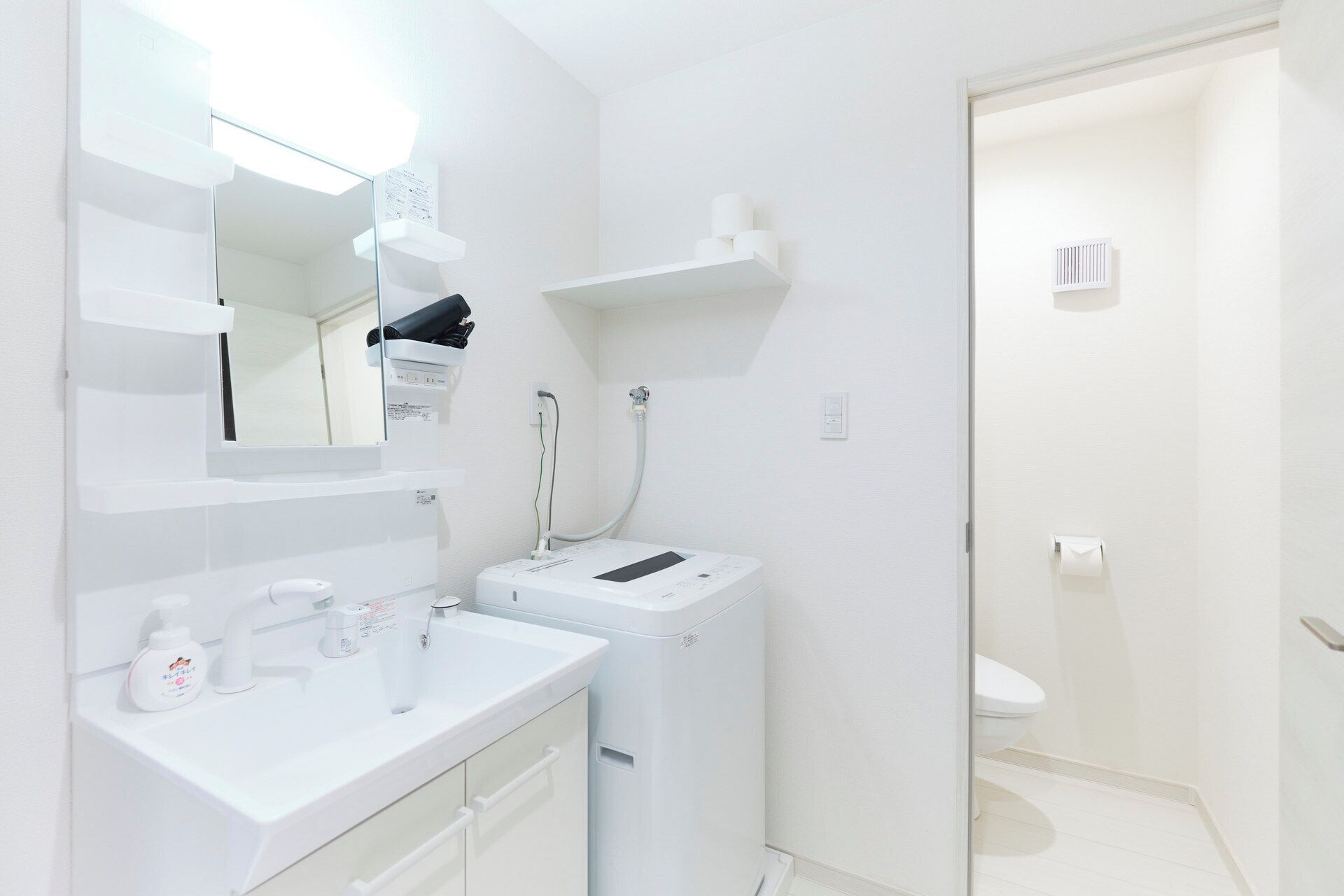 A modern bathroom with a white sink, mirror, and toilet.