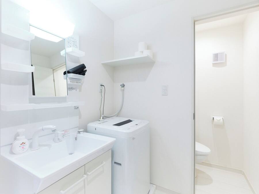 Un baño moderno con lavamanos, espejo y retrete blancos.