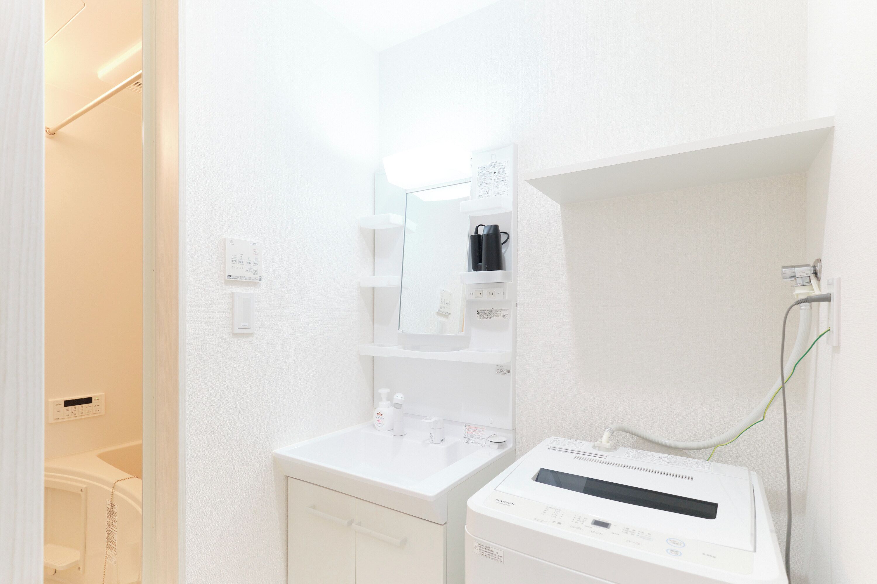 Un bagno pulito e luminoso con lavandino, specchio e una lavatrice bianca.