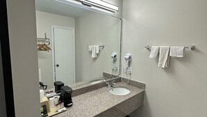 A modern bathroom with a granite countertop, a sink, a mirror, a towel rack, and a hairdryer.