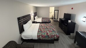 A hotel room with two beds, a TV, a desk, and a mirror.