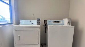 Two front-loading Whirlpool washers in a laundry room with a window and a wall-mounted electrical outlet.