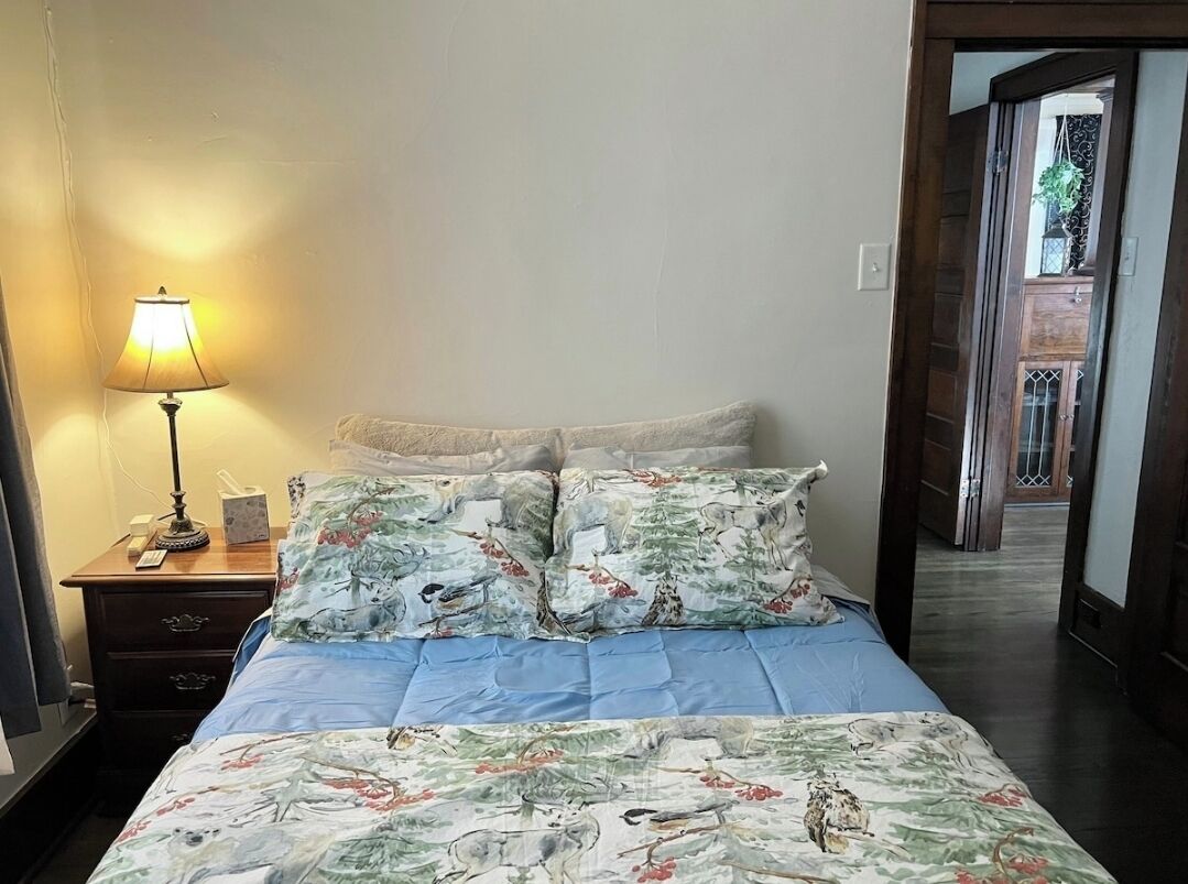 Une chambre à coucher avec un lit, une table de chevet, une lampe et une vue sur un escalier en bois.