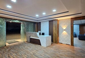 A modern reception area with a marble counter, wooden flooring, and a patterned wall. - Hotel Park View Pithampur (Pithampur)