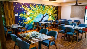 A conference room with multiple tables and chairs, a large mural on the wall, and a projector screen.