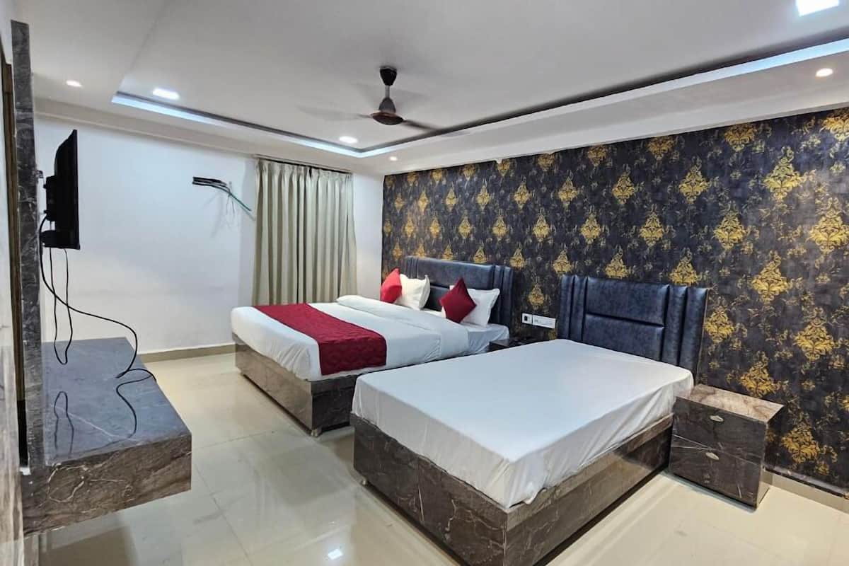 A hotel room with two beds, a flat-screen TV, a ceiling fan, and a marble accent wall.