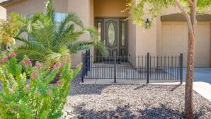 Un immeuble résidentiel doté d’une entrée sécurisée par un portail, d’un garage et d’un espace paysager agrémenté d’un palmier et de plantes à fleurs.