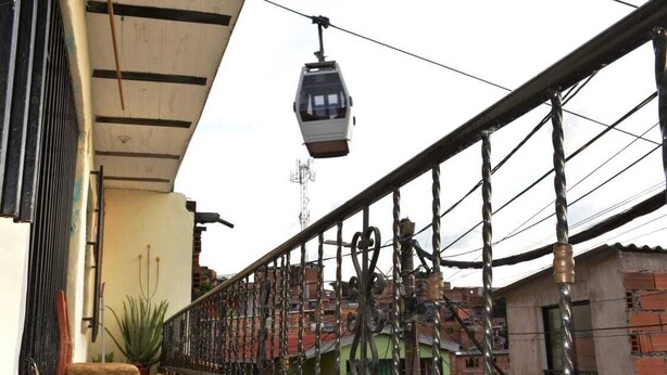 A balcony with a chair, a potted plant, and a cable car in the background. - BEAUTIFUL FAMILY ROOM. (Medellín)
