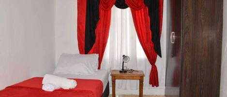 Una habitación de hotel con cama, mesita de noche de madera, espejo y armario.