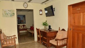 A dining area with a wooden table and chairs, a clock on the wall, and a door labeled B02. - BEAUTIFUL FAMILY ROOM. (Medellín)