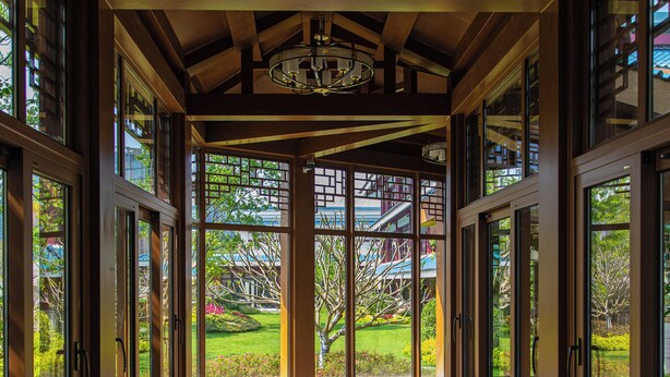 A corridor with large windows, a ceiling fan, and a view of a playground.