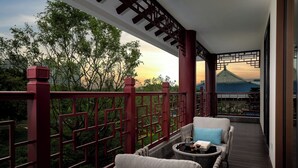 A balcony with wicker furniture, a view of trees, and a traditional building in the background.