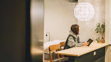 A person reading at a wooden desk in a room with a large, textured pendant light.