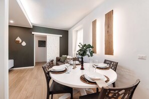 A dining area with a round table, chairs, and a plant centerpiece. - Rafael White Home - MyHomeinComo (Como)