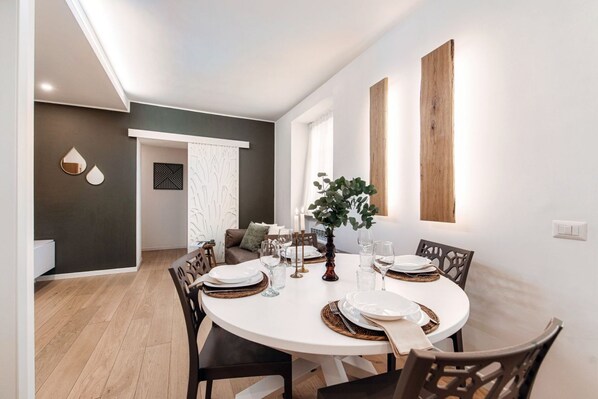 Een eethoek met een ronde tafel, stoelen en een plant als decoratie.
