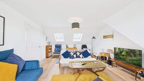 Uma sala de estar moderna com sofá, mesa de centro, televisão e estante.