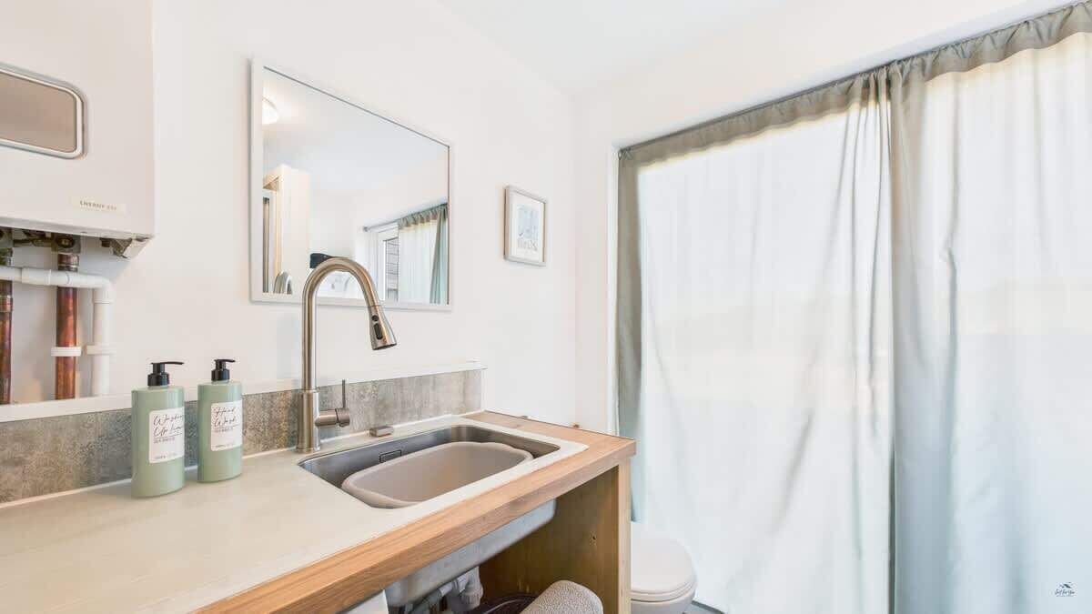 Een badkamer met een wastafel, spiegel en twee flessen handzeep.