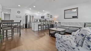 A modern kitchen with white cabinets, a central island, and a dining area with chairs. - Spacious Getaway Near FL Attractions, Plunge Pool, Game Room, Firepit, BBQ, Pet-Friendly & Sleeps 10 (Brooksville)