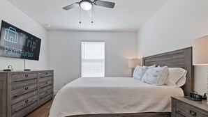 A bedroom with a bed, a nightstand, a dresser, a ceiling fan, a TV displaying 'iTrip Palm Harbor', and a window with blinds. - Spacious Getaway Near FL Attractions, Plunge Pool, Game Room, Firepit, BBQ, Pet-Friendly & Sleeps 10 (Brooksville)