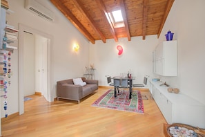 A modern living room with a wooden ceiling, a sofa, a dining table, and a kitchen area. - Morgante Salo-lake View & Parking (Salò)