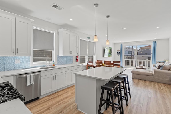 A modern kitchen with white cabinets, a central island, and a dining area with bar stools.
