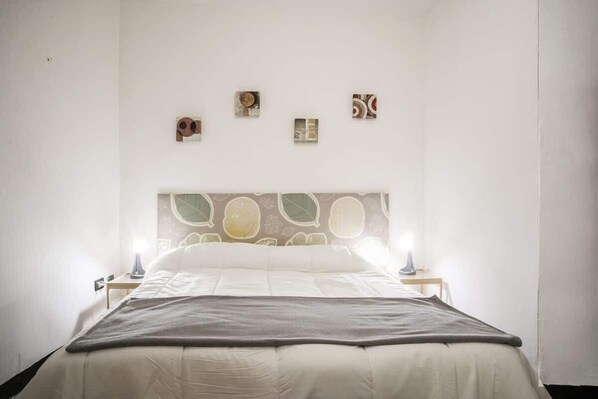 A bedroom with a bed, two bedside tables, and three wall-mounted artworks.