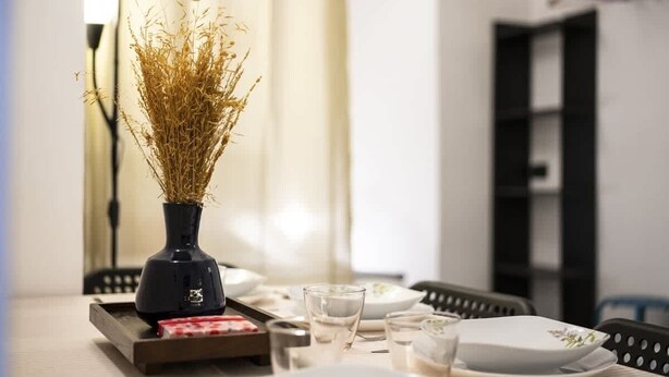 Una taula de dinar amb un ram de plantes seques, vasos i plats.