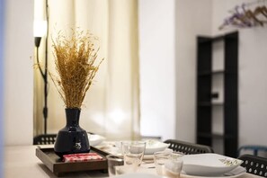 A dining table with a vase of dried plants, glasses, and plates.