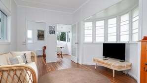 A spacious living room with a large window, a television, and a cozy seating area. - The Castaway (Emu Park)