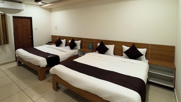 A hotel room with two beds, a ceiling fan, and an air conditioning unit. - Hotel Ayodhya Bhwan (Dwarka)