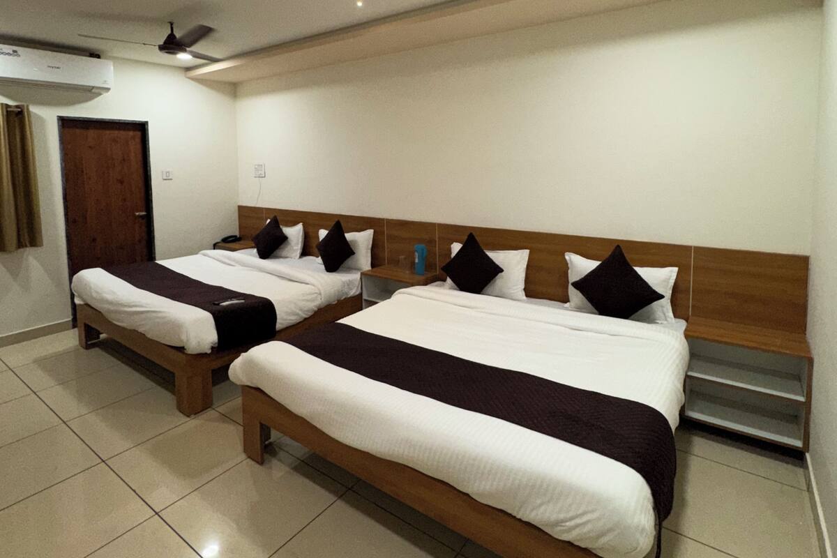 Una habitación de hotel con dos camas, ventilador de techo y aire acondicionado.