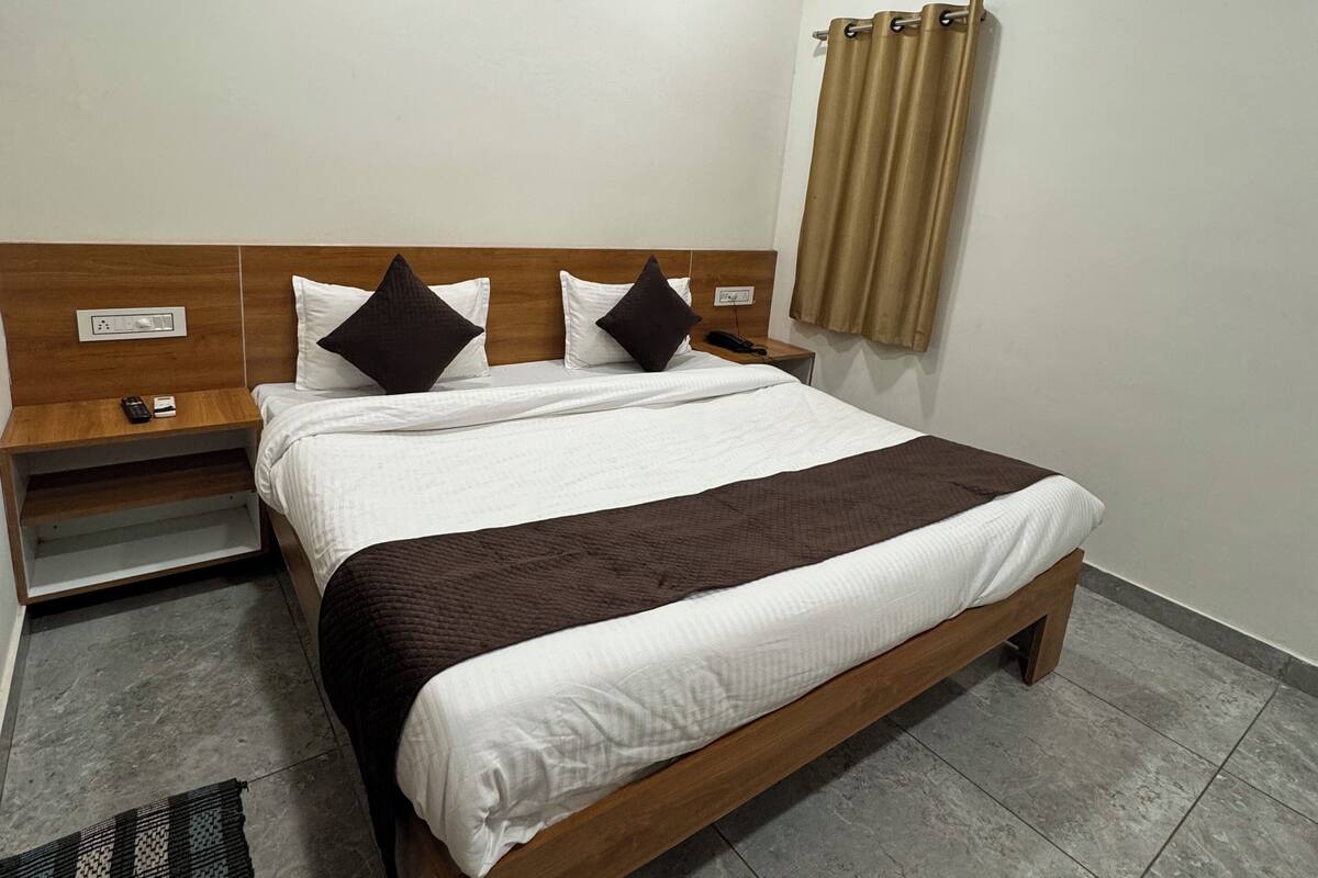 Una habitación de hotel ordenada con una cama, mesita de noche y una pequeña alfombra.