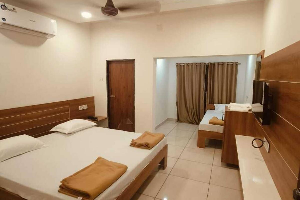 Habitación de hotel con dos camas, un escritorio, un televisor y un equipo de aire acondicionado.