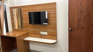 A wooden wall-mounted TV with a power outlet below it. - Hotel Ayodhya Bhwan (Dwarka)