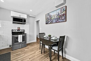 A modern kitchen with white cabinetry, a stainless steel oven, and a dining area with a table and chairs.