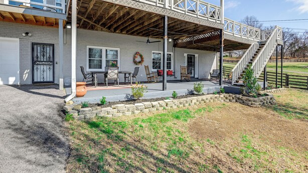 A two-story house with a covered porch, a staircase, and a brick exterior. - Rustic Cowboy Ranch Retreat: Stay Near Nashville (Antioch)
