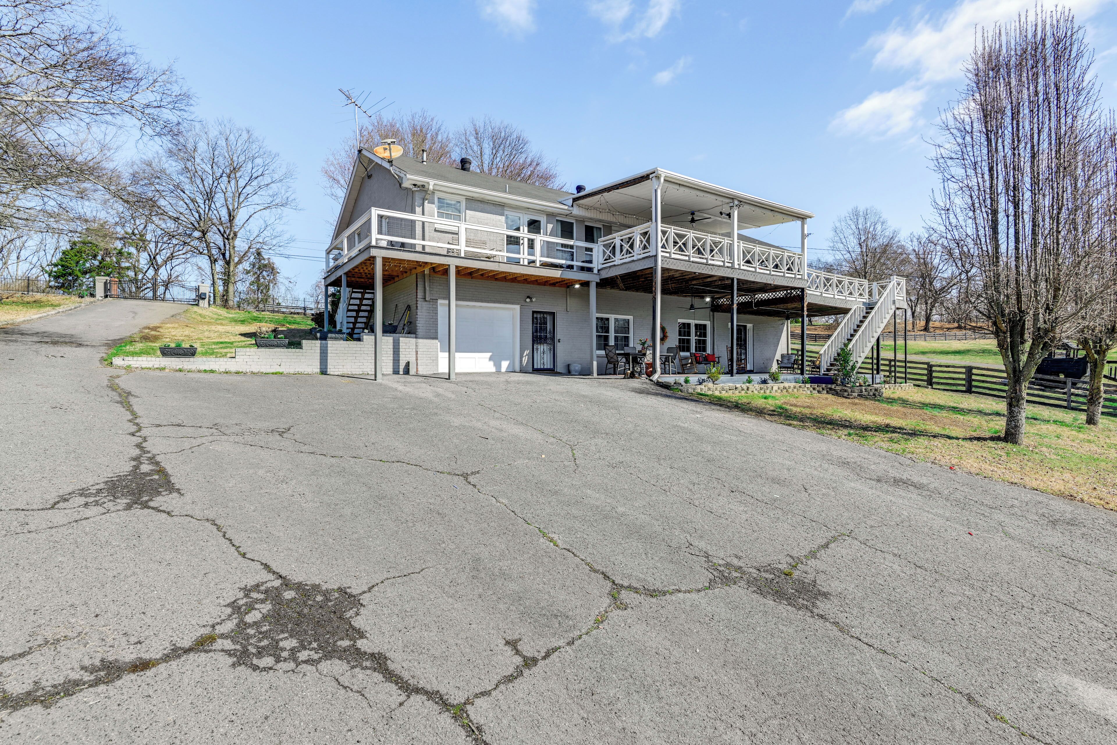 A two-story building with a covered patio area, a staircase leading to the upper level, and a driveway.