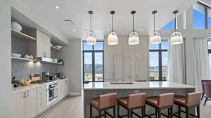 A modern kitchen with a large island, pendant lights, and a view of the mountains. - Luxury Corner Suite, Private Hot Tub, walk to lift (Park City)