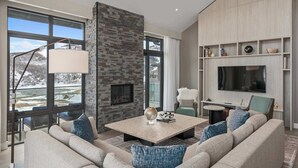 A modern living room with a fireplace, large windows, a flat-screen TV, and a cozy seating area. - Luxury Corner Suite, Private Hot Tub, walk to lift (Park City)