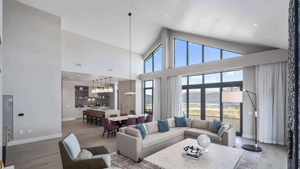 A spacious living area with a large sectional sofa, a round coffee table, and a dining area with a kitchen in the background. - Luxury Corner Suite, Private Hot Tub, walk to lift (Park City)