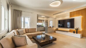 A modern living room with a sofa, coffee table, and TV. - Villa Serenity- Modern villa for an exclusive vacation in Crete (Kournás)