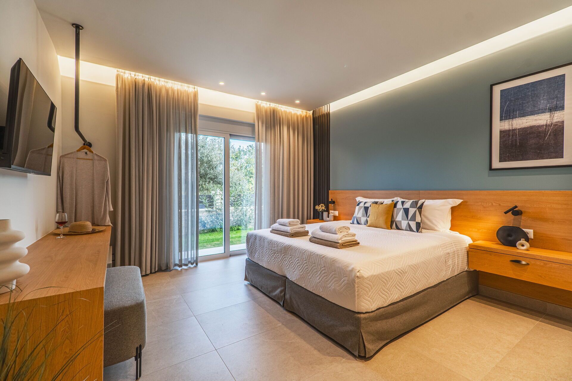 Habitación de hotel moderna con una cama grande, un escritorio, una silla y vistas al exterior.