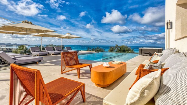 A poolside area with lounge chairs, a small table, and umbrellas.