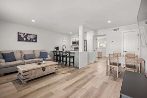 Ein modernes Wohnzimmer mit Sofa, Couchtisch und Essbereich mit Stühlen und einem Tisch.